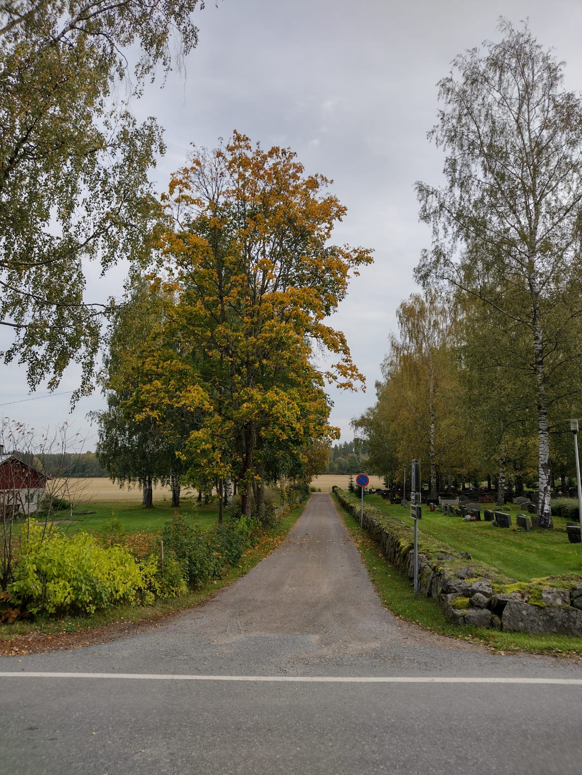 Nimeä vailla oleva hiekkatie hautausmaan muurin kupeessa