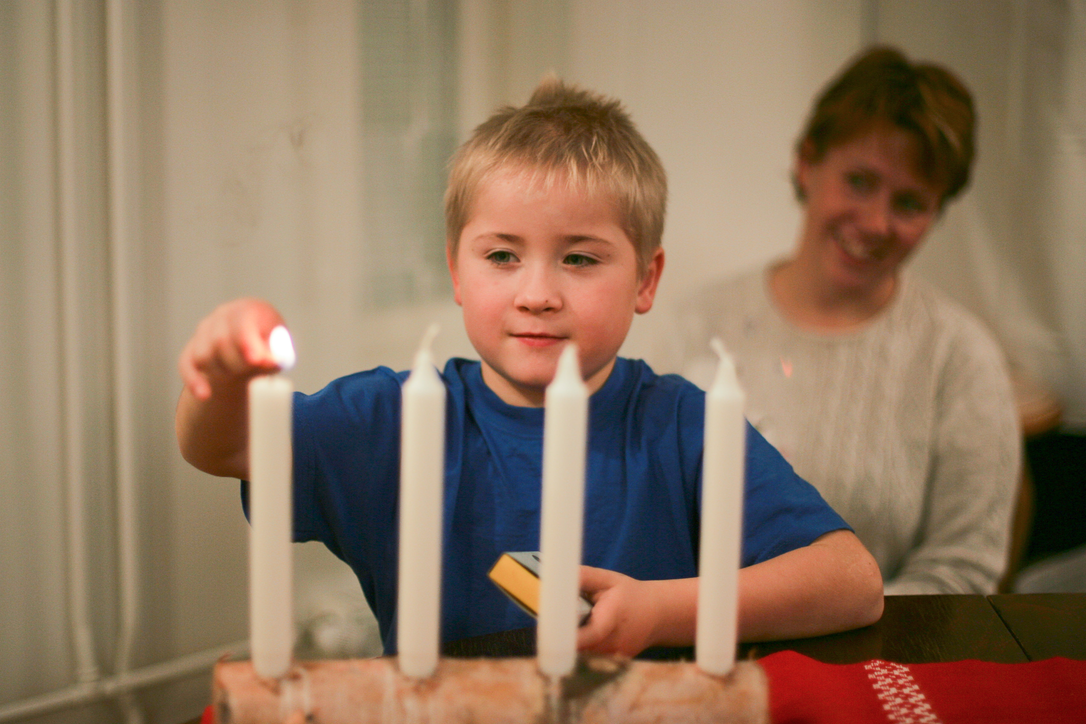 Messu Pyhän Laurin kirkossa 7-vuotias Teemu sytyttää 1. adventtikynttilää äidin katsellessa.