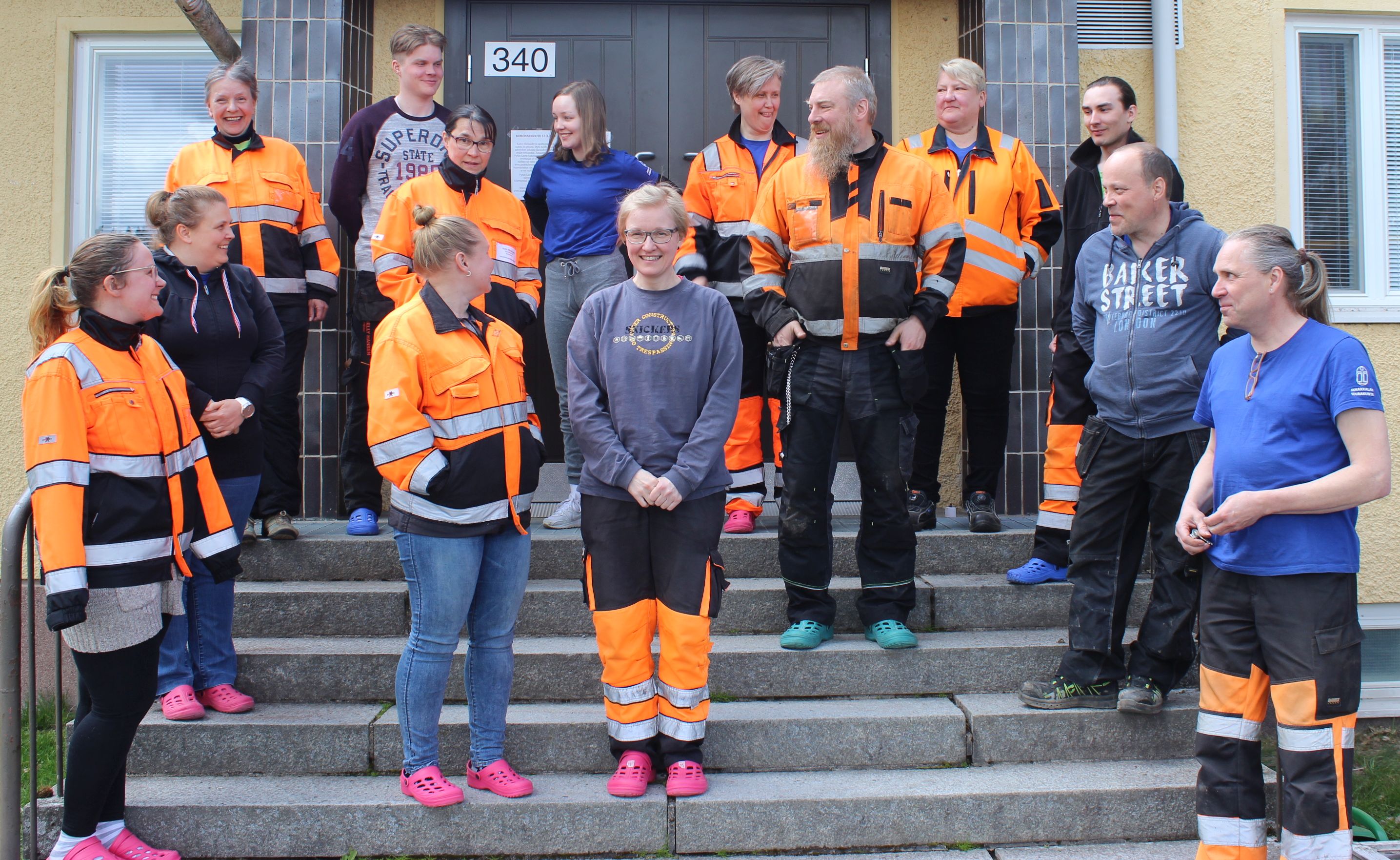 Hautausmaan vakihenkilökunta poseeraa yhdessä kausityöntekijöiden kanssa Tarinmaan seurakuntatalon portailla. 